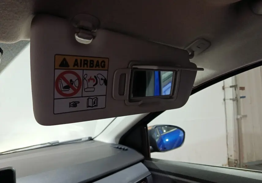 Vue intérieure côté passager du pare-soleil avec miroir et avertissement airbag, reflet bleu de la Dacia Sandero Extreme+ 2024.