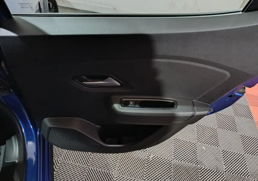 Vue rapprochée de la porte avant gauche bleu foncé de la Dacia Sandero Extreme+ avec commande de vitre électrique.