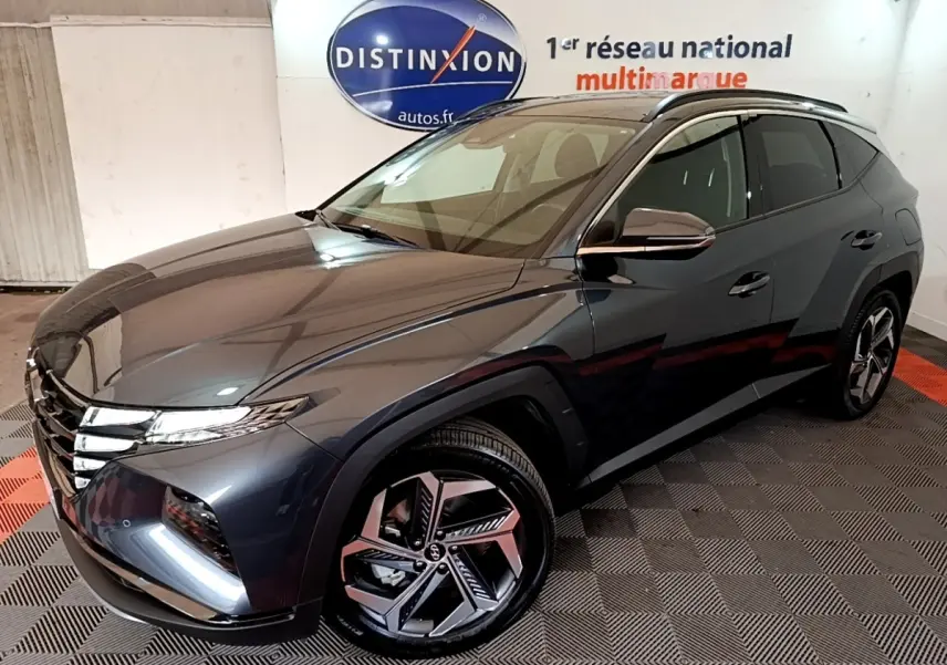 Vue 3/4 avant droite du Hyundai Tucson gris foncé 2022 avec jantes alliage et toit noir en intérieur showroom.