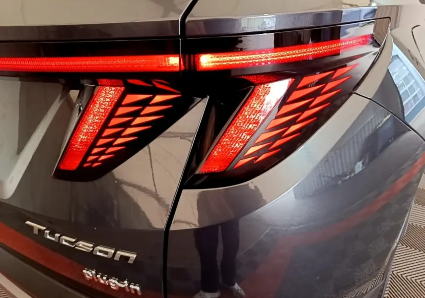 Gros plan sur le feu arrière droit allumé du Hyundai Tucson gris foncé avec logo et éclairage LED distinctif.