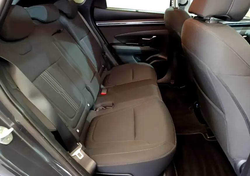 Vue intérieure côté gauche des sièges arrière gris foncé du Hyundai Tucson 2022, avec portières et ceintures visibles.