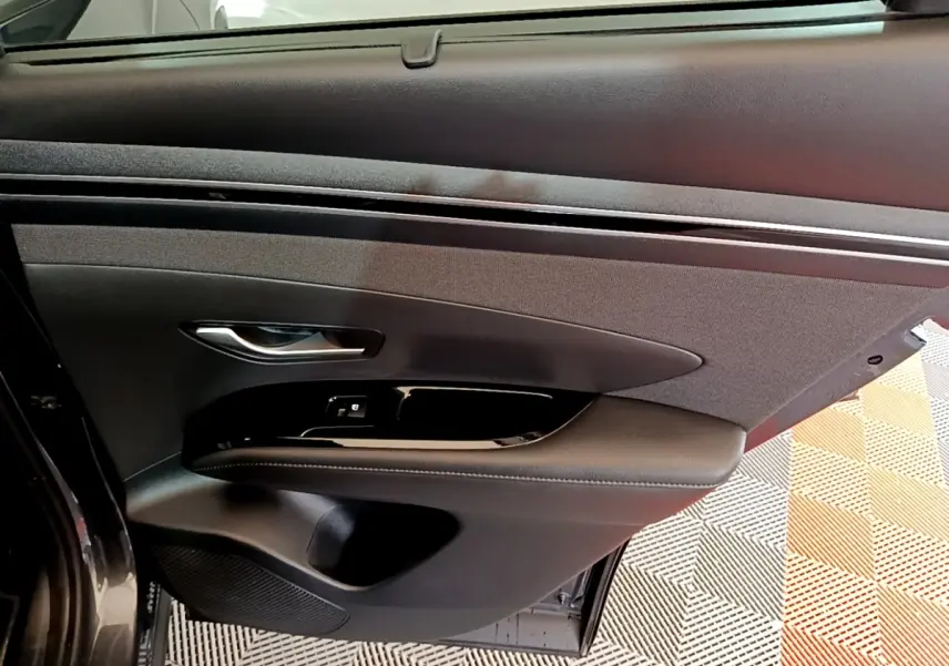 Vue intérieure de la porte arrière droite du Hyundai Tucson 2022, revêtement noir avec commande de fenêtre intégrée.