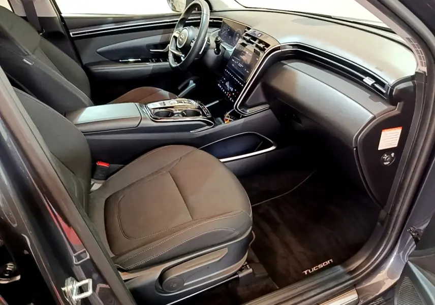 Intérieur du Hyundai Tucson gris foncé vu côté passager, avec tableau de bord moderne et sièges noirs.