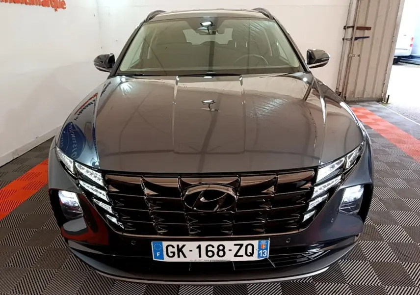 Vue avant d'un Hyundai Tucson gris foncé 2022 avec calandre noire et phares LED allumés en intérieur.