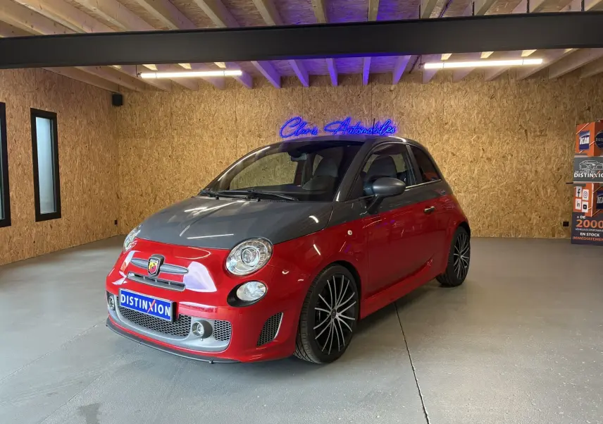 Vue 3/4 avant droite d'une Abarth 500 Competizione 2016 rouge et gris avec jantes noires en intérieur showroom.