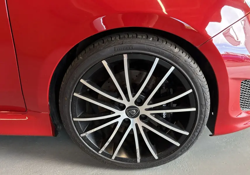 Gros plan sur la roue avant droite de l'Abarth 500 Competizione rouge et gris, avec jante noire à branches fines argentées.