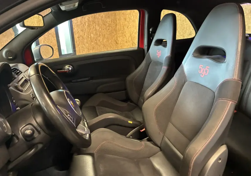 Vue intérieure côté conducteur de l'Abarth 500 Competizione 2016, sièges sport noirs avec logo 595 rouge et détails rouges.