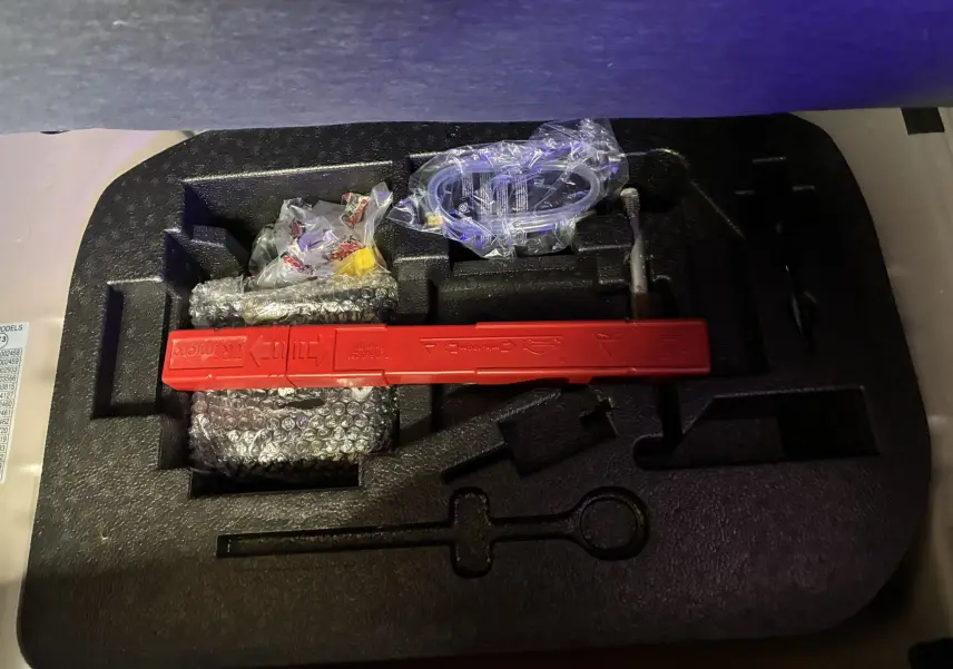 Coffret d’outils de bord avec triangle de signalisation rouge, présenté en vue plongeante sur mousse noire.