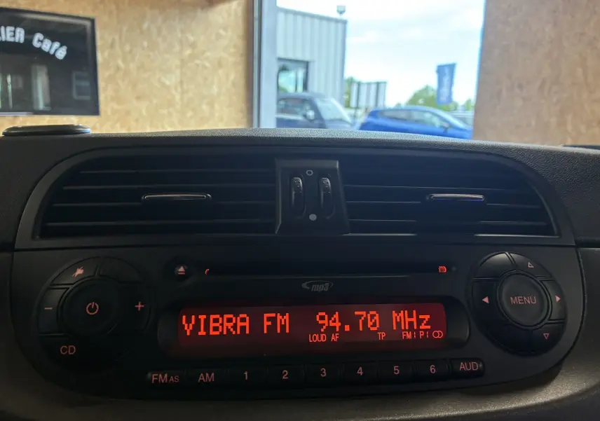 Vue intérieure centrée sur la radio affichant la fréquence 94.7 MHz dans un Abarth 500 Competizione rouge et gris de 2016.