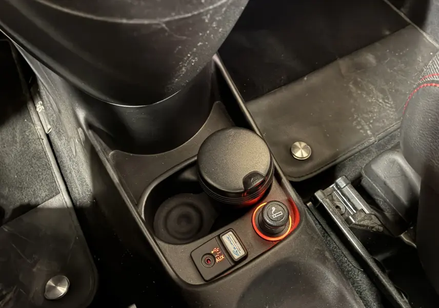 Gros plan sur la console centrale de l'Abarth 500 Competizione 2016, avec allume-cigare et prise auxiliaire éclairés.