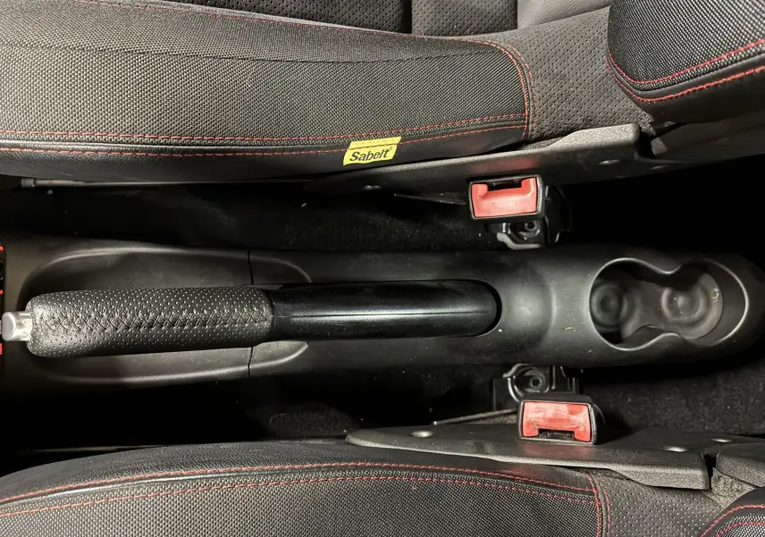 Vue plongeante sur le frein à main et les sièges noirs avec surpiqûres rouges de l'Abarth 500 Competizione 2016.