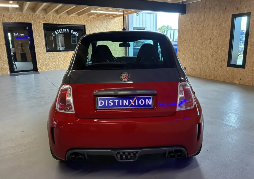 Vue arrière d'une Abarth 500 Competizione 2016 rouge et gris avec double sortie d'échappement, en intérieur.