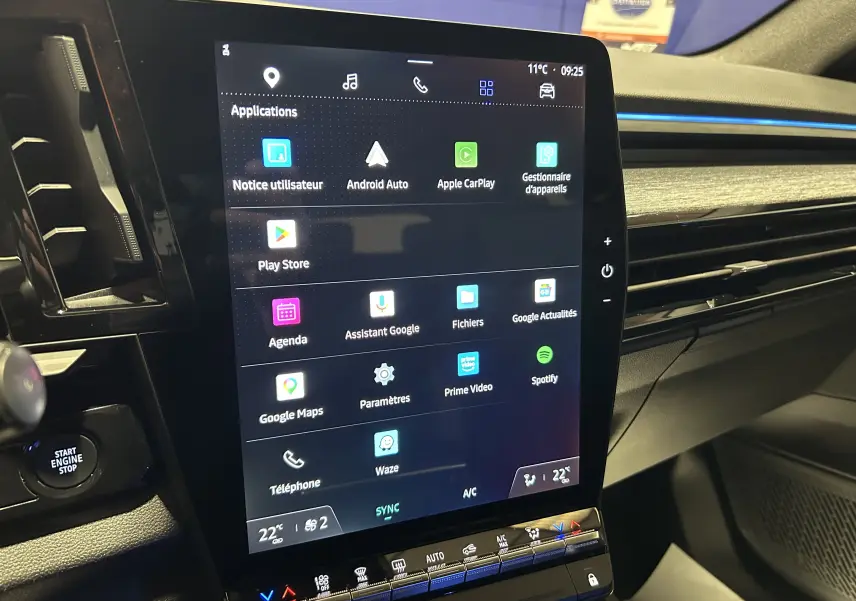 Écran tactile central du Renault Austral 2024 affichant les applications connectées, avec tableau de bord noir et détails bleus.