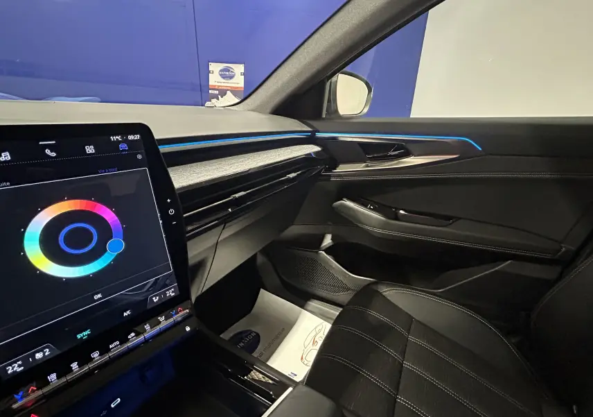 Vue intérieure côté passager du Renault Austral blanc nacré 2024, avec éclairage d'ambiance bleu et écran tactile central.