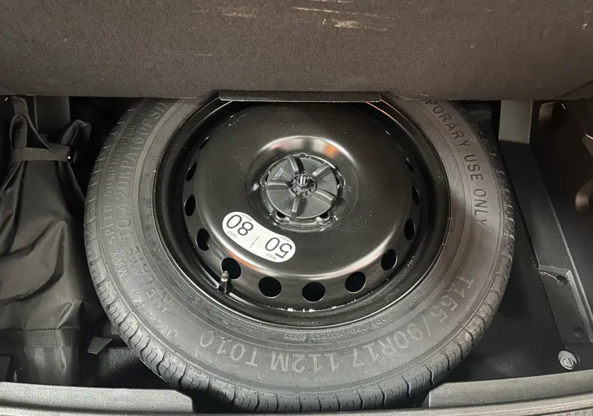 Gros plan sur la roue de secours temporaire noire dans le coffre du Renault Austral blanc nacré 2024.