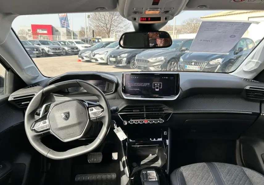 Vue intérieure avant de la Peugeot 208 Hybrid 110 e-DCS6 Allure 2024, tableau de bord moderne avec écran tactile et volant compact.