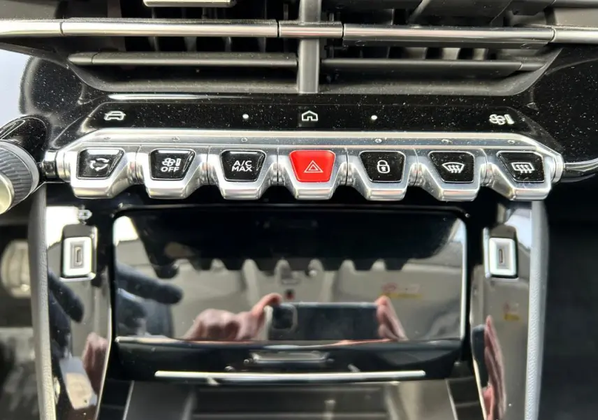 Détail de la console centrale du Peugeot 208 Hybrid 110 Allure 2024, avec boutons chromés et bouton rouge d’alerte.