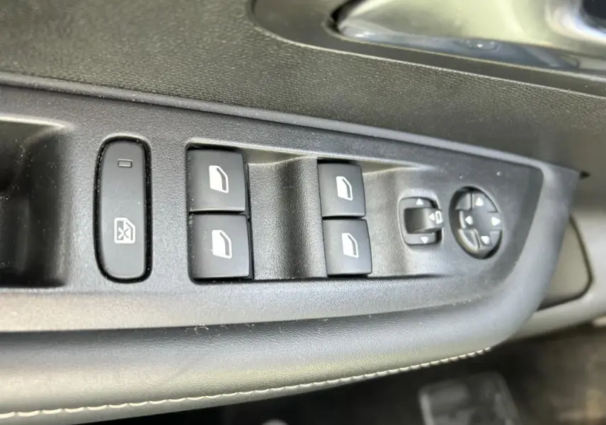 Gros plan sur les commandes des vitres et rétroviseurs côté conducteur de la Peugeot 208 Hybrid 110 e-DCS6 Allure 2024.