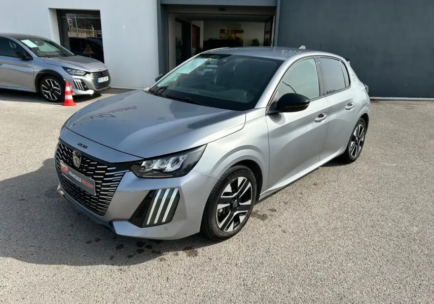 Peugeot 208 Hybrid gris vue 3/4 avant droit, avec calandre distinctive et feux LED verticaux marquants.