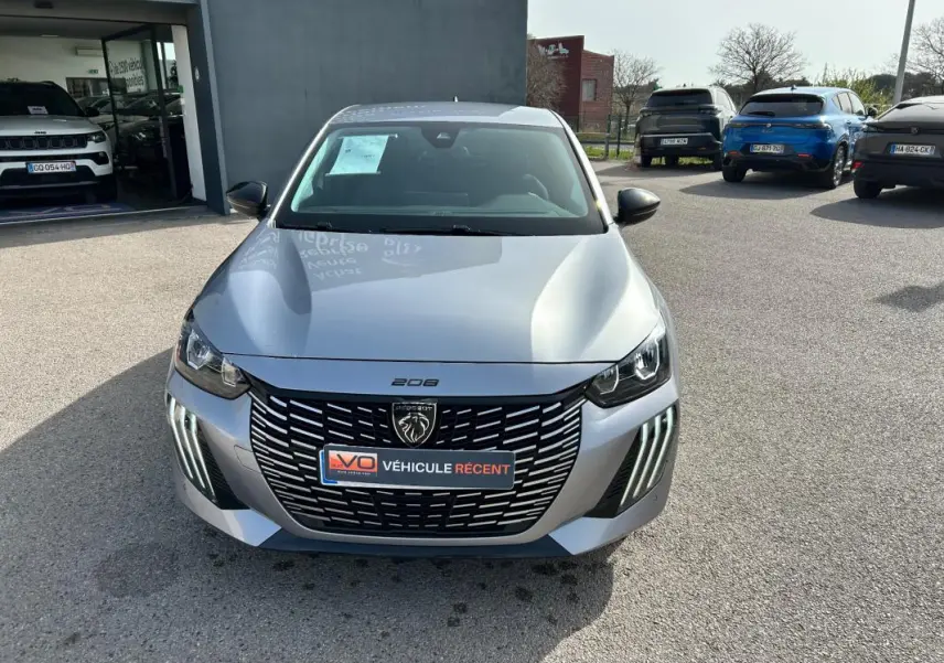 Peugeot 208 Hybrid 110 e-DCS6 Allure gris vue de face, avec calandre noire et feux diurnes LED verticaux.