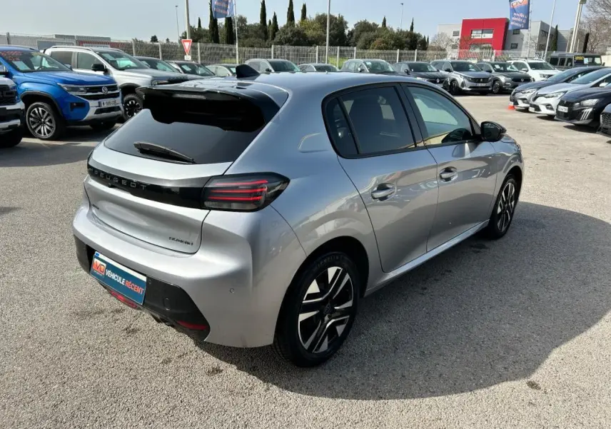 Peugeot 208 Hybrid 110 gris vue 3/4 arrière droit, feux arrière LED et jantes alliage distinctives visibles.