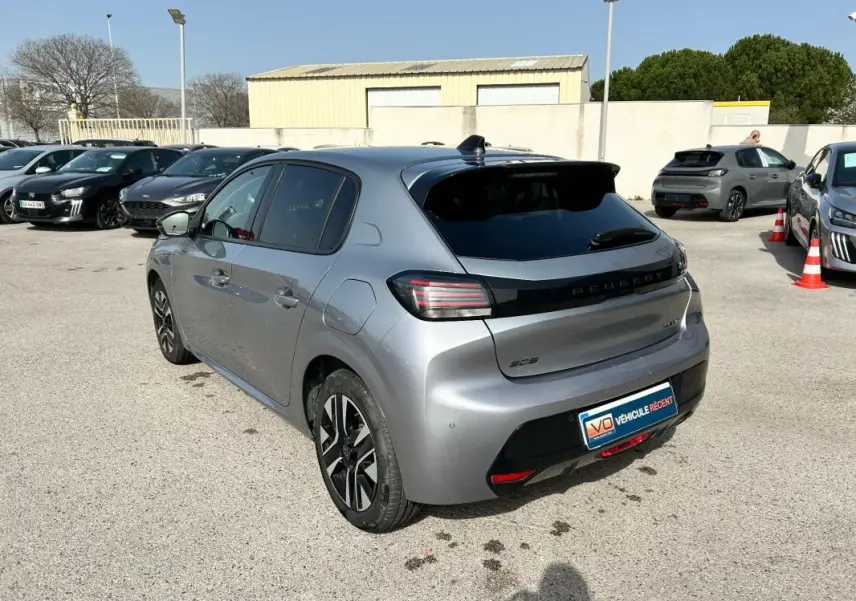Peugeot 208 Hybrid gris vue 3/4 arrière droit, avec feux arrière distinctifs et jantes noires bicolores.