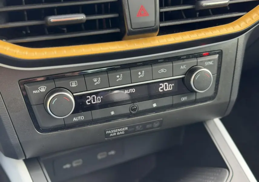 Gros plan sur la console centrale de la SEAT Arona TSI 115 Style 2025, montrant la climatisation automatique bi-zone avec cadre jaune.