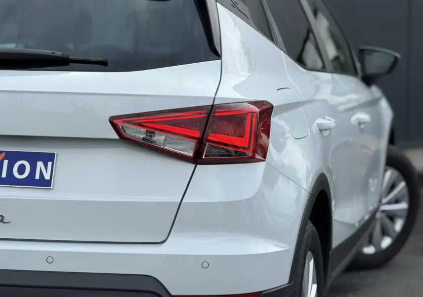 Vue arrière côté gauche d'un SEAT Arona blanc alpin avec feux arrière LED et jantes alliage 16 pouces.