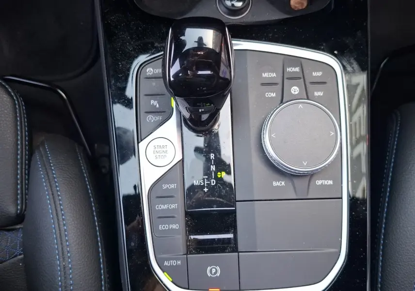 Vue plongeante sur la console centrale noire brillante de la BMW Série 1 118D M Sport avec levier de vitesse et commandes.