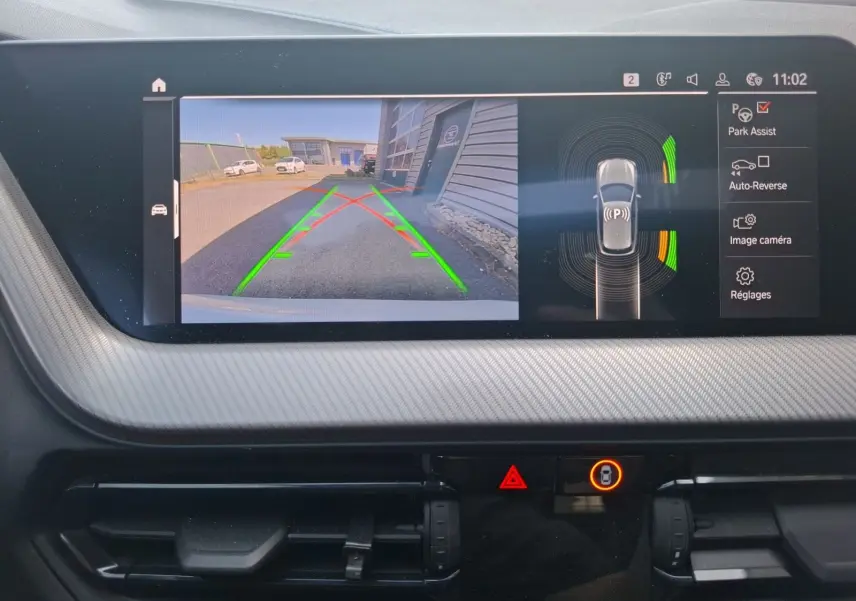 Écran de caméra de recul et radar de stationnement actif dans le tableau de bord d'une BMW Série 1 blanche.