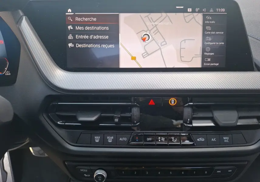 Vue rapprochée de la console centrale de la BMW Série 1 118D M Sport blanche, affichant l'écran GPS et commandes climatisation.