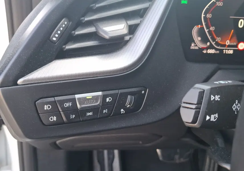 Gros plan sur les commandes d’éclairage et la commande au volant côté gauche d’une BMW Série 1 118D M Sport.