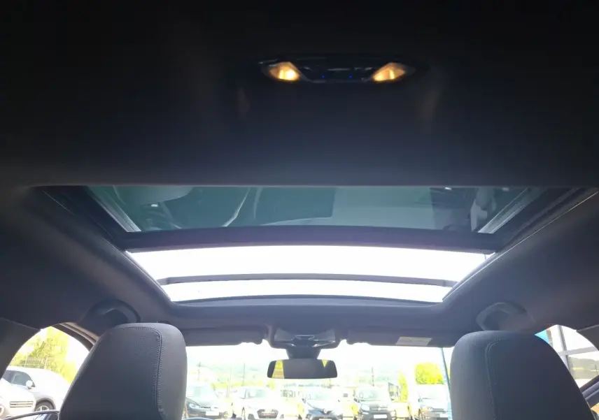 Vue intérieure du toit ouvrant panoramique de la BMW Série 1 118D M Sport blanche avec sièges avant visibles.
