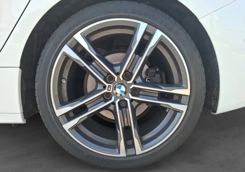 Gros plan sur la jante alliage 18 pouces M Sport noire et argentée de la BMW Série 1 blanche côté arrière droit.