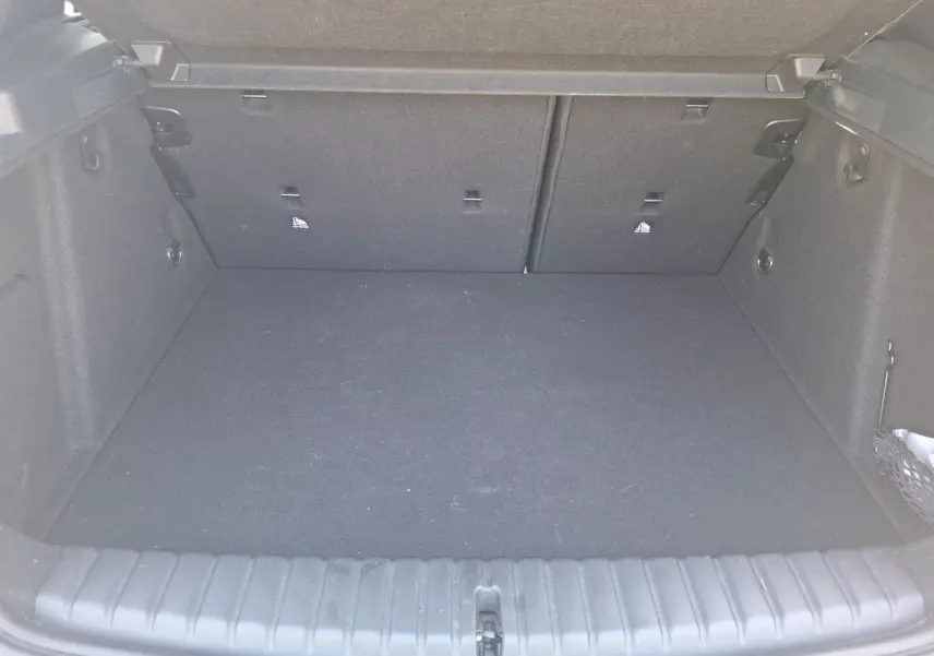 Coffre vide en vue plongeante d'une BMW Série 1 118D M Sport blanche, montrant l'espace de chargement et les fixations Isofix.