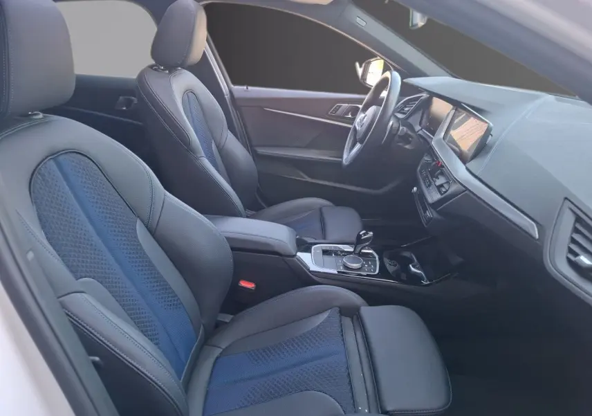 Vue intérieure côté conducteur de la BMW Série 1 118D M Sport avec sièges baquets cuir et tissu noirs et bleus.