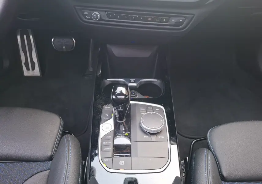 Vue plongeante sur la console centrale de la BMW Série 1 118D M Sport blanche, avec levier de vitesse et commandes multimédia.