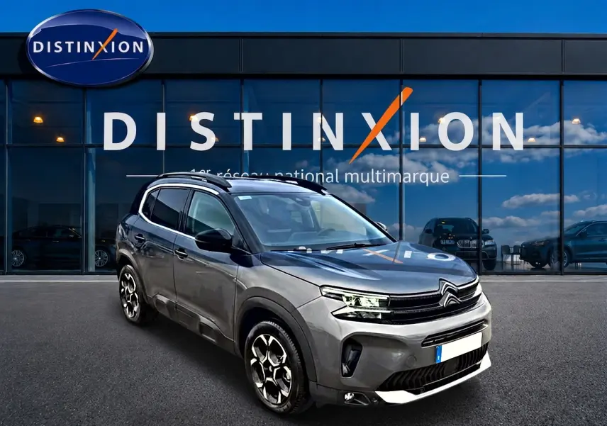 Citroën C5 Aircross gris vue 3/4 avant droit, avec jantes alu et barres de toit devant showroom Distinxion.