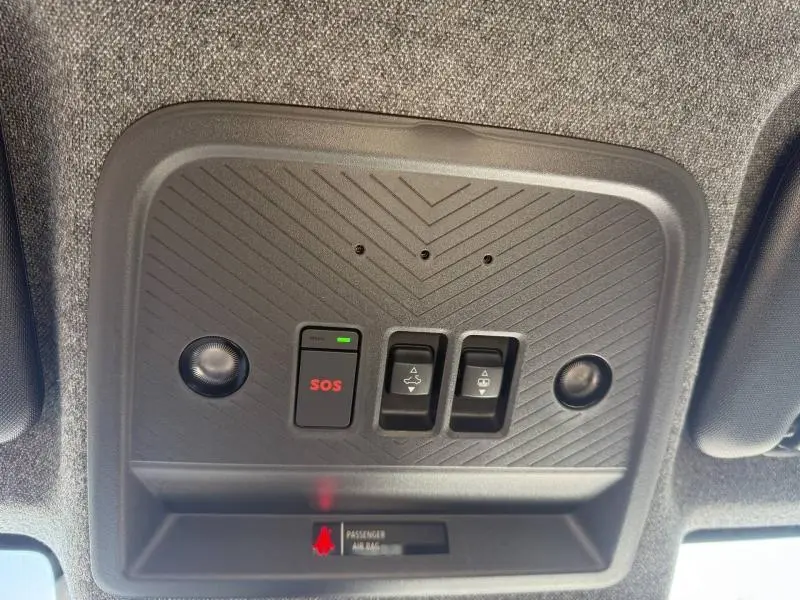 Vue en contre-plongée du panneau de commande au plafond avec bouton SOS et éclairages dans un Dacia Bigster gris Schiste 2025.