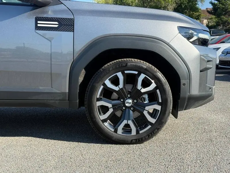 Gros plan sur la roue avant droite du Dacia Bigster gris schiste, avec jante alu bicolore et partie avant du véhicule visible.