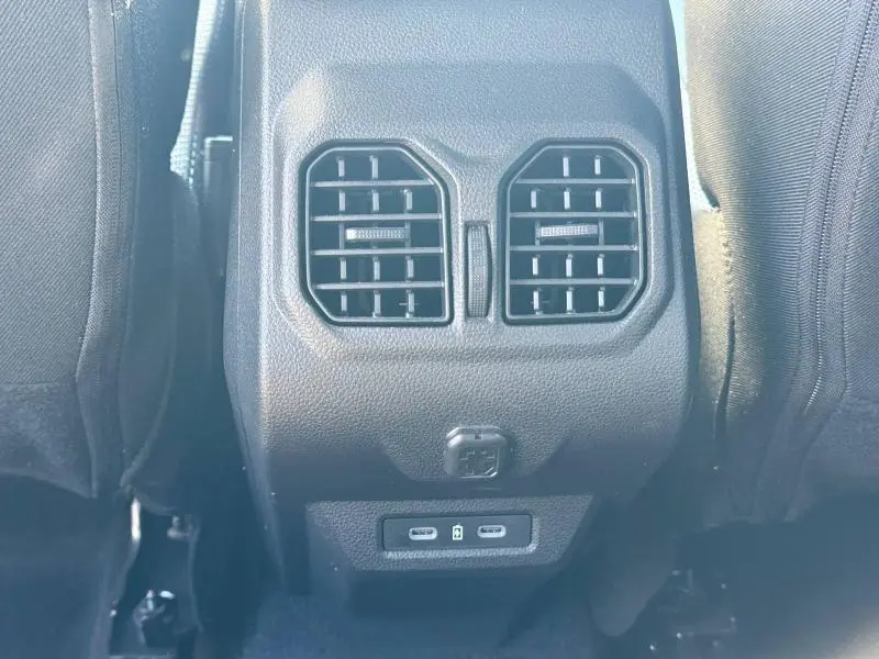 Vue rapprochée des aérateurs arrière et ports USB du Dacia Bigster gris schiste, entre les sièges avant.