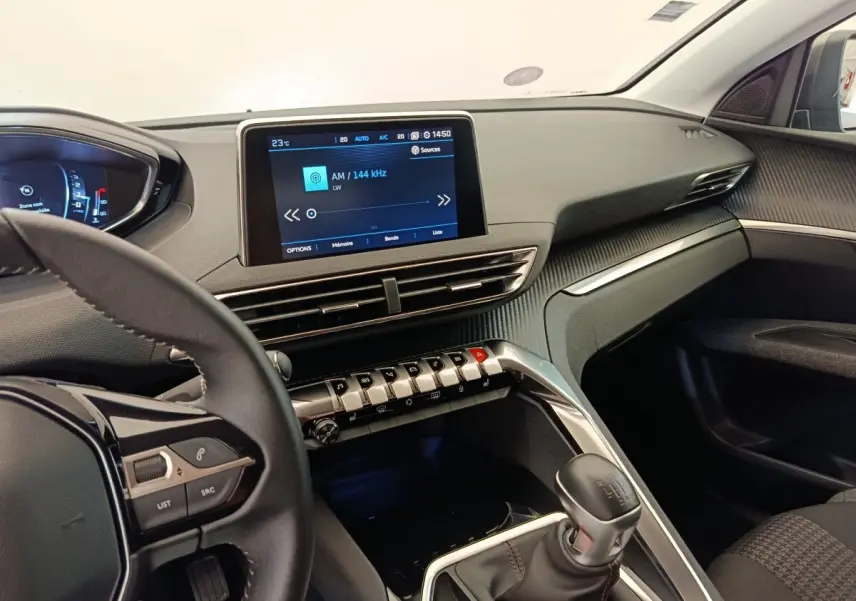 Intérieur du Peugeot 3008 2020, vue côté conducteur, tableau de bord noir avec écran tactile central et levier de vitesse manuel.