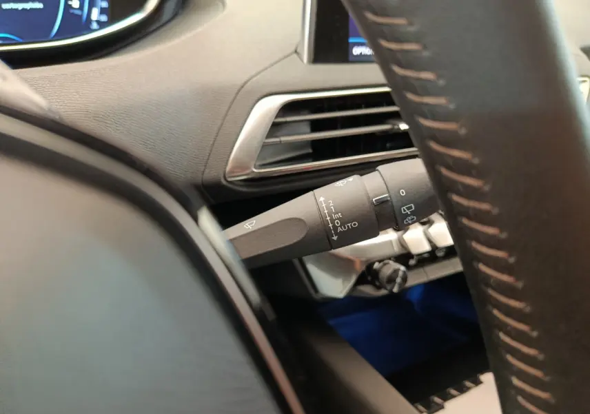 Gros plan sur la manette d'essuie-glace à gauche du volant cuir dans l'habitacle gris foncé du Peugeot 3008 2020.
