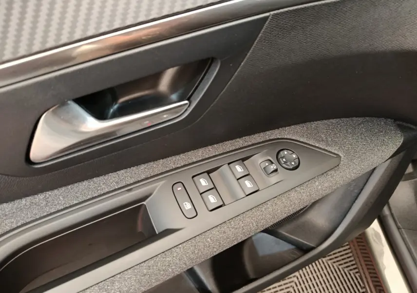 Gros plan sur la porte côté conducteur du Peugeot 3008 gris foncé, montrant les commandes des vitres et le bouton de verrouillage.
