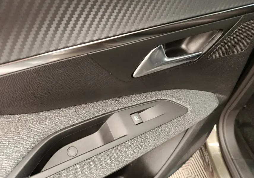 Détail de la porte côté conducteur du Peugeot 3008 gris foncé, montrant la poignée et le bouton de verrouillage électrique.