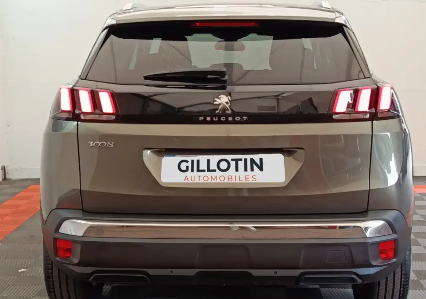Vue arrière d'un Peugeot 3008 gris foncé avec feux arrière LED caractéristiques allumés et logo central visible.