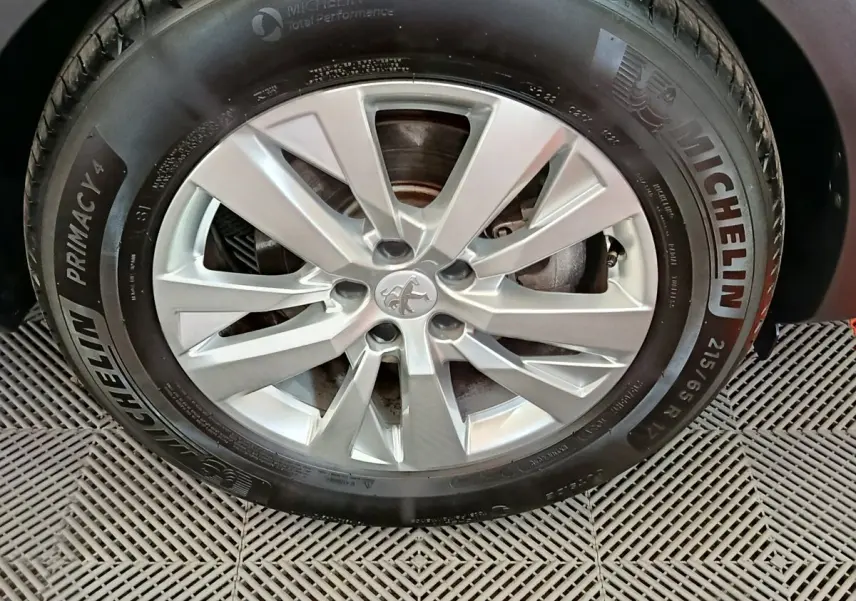 Gros plan sur la roue avant droite d’un Peugeot 3008 gris foncé avec jante alliage et pneu Michelin Primacy 4.