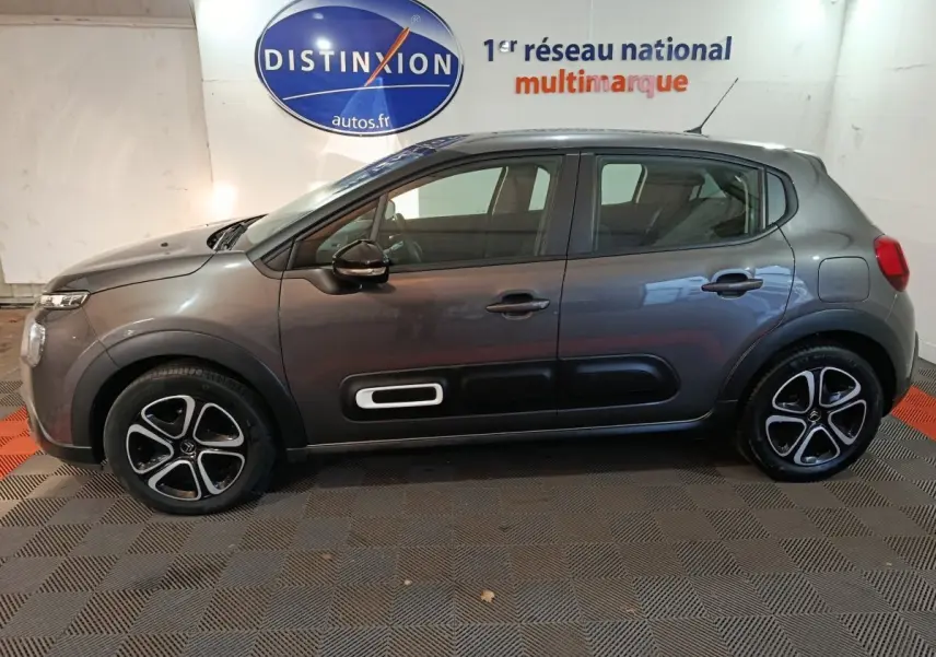 Profil droit d'une Citroën C3 BlueHDi 100 BVM PLUS gris foncé avec protections latérales noires et jantes stylisées.