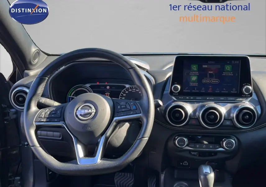 Vue intérieure du tableau de bord du Nissan Juke Hybrid 2024, avec volant cuir noir et écran tactile central.