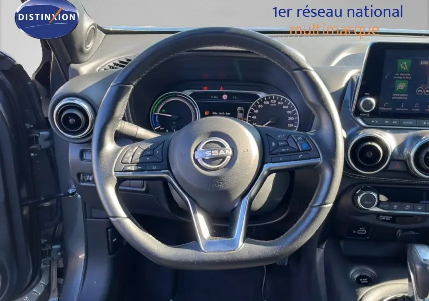 Vue intérieure centrée sur le volant Nissan Juke gris squale métal, avec tableau de bord et écran tactile visibles.
